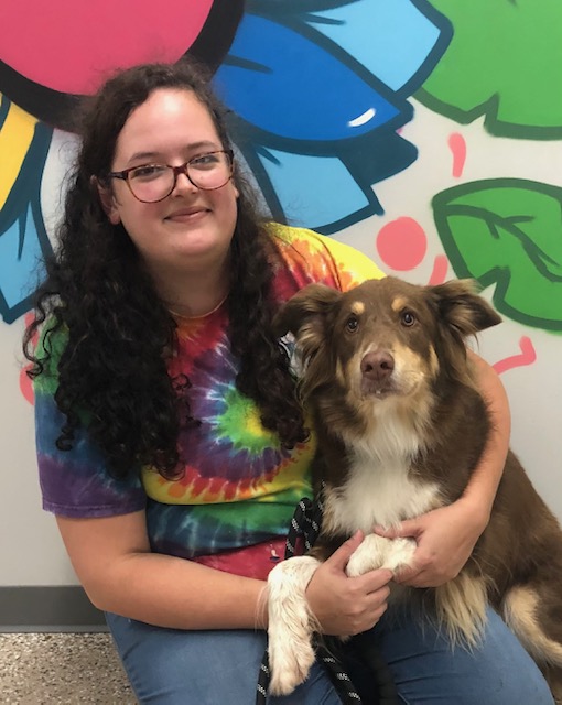 dark brown curly haired woman snuggling a white dog